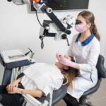 Dentystka wykonująca leczenie kanałowe pod mikroskopem u pacjentki
